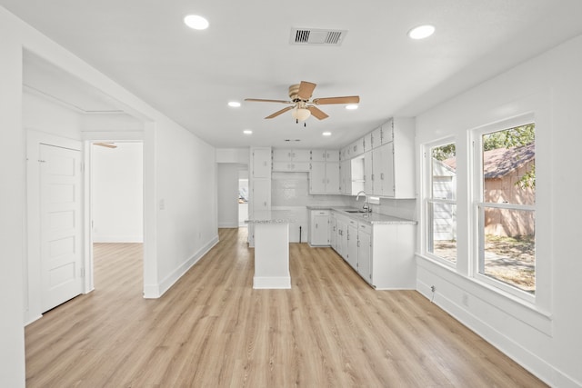 kitchen with light hardwood / wood-style floors, white cabinets, sink, tasteful backsplash, and ceiling fan