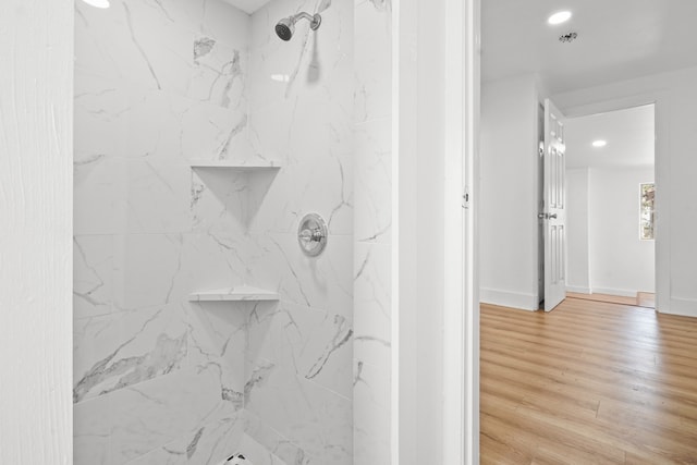 bathroom with wood-type flooring and tiled shower