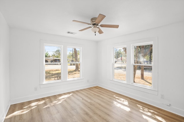 empty room featuring a wealth of natural light, ceiling fan, and light wood-type flooring