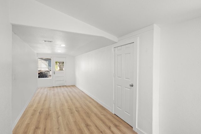 corridor featuring lofted ceiling and light hardwood / wood-style flooring