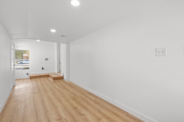 hallway with lofted ceiling and light hardwood / wood-style floors