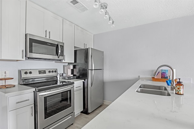 kitchen featuring sink, appliances with stainless steel finishes, a textured ceiling, and white cabinets