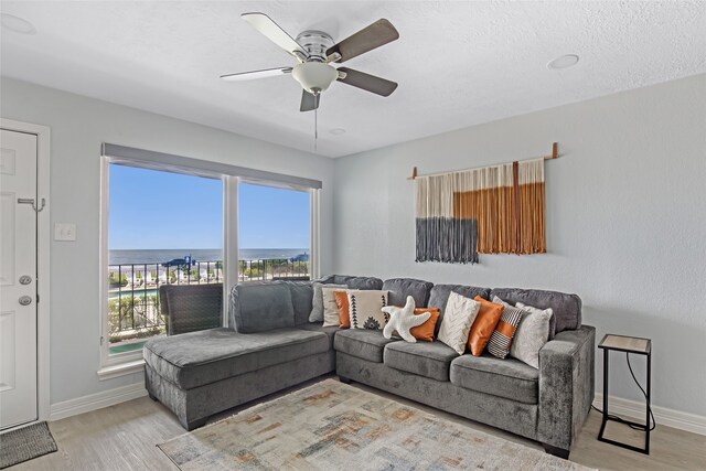 living room featuring a textured ceiling, ceiling fan, and light hardwood / wood-style flooring