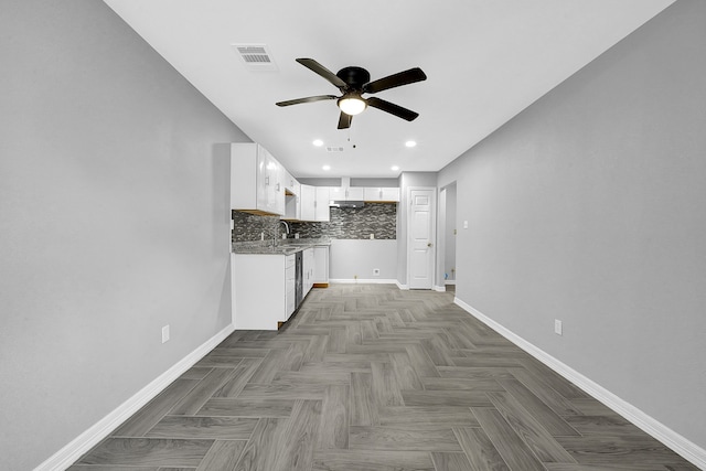 kitchen featuring backsplash, light stone countertops, sink, white cabinets, and ceiling fan