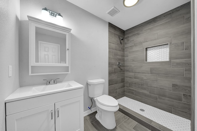 bathroom with toilet, vanity, and a tile shower