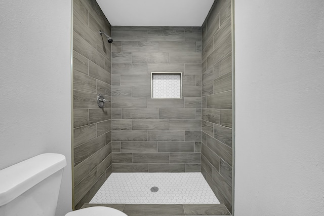 bathroom with toilet and a tile shower