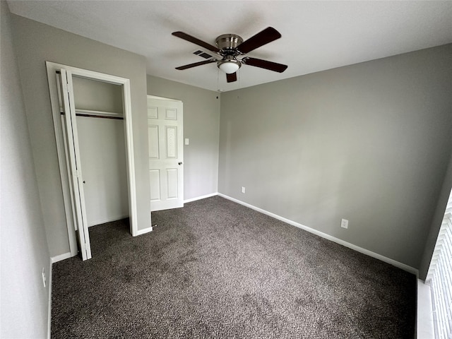 unfurnished bedroom with ceiling fan, a closet, and dark carpet