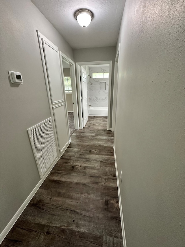 hall with a textured ceiling and dark hardwood / wood-style flooring