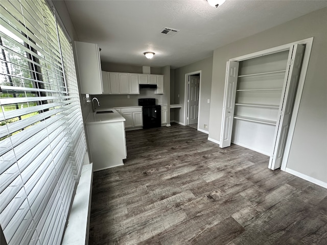 kitchen with dark hardwood / wood-style flooring, black range with electric cooktop, sink, and white cabinets