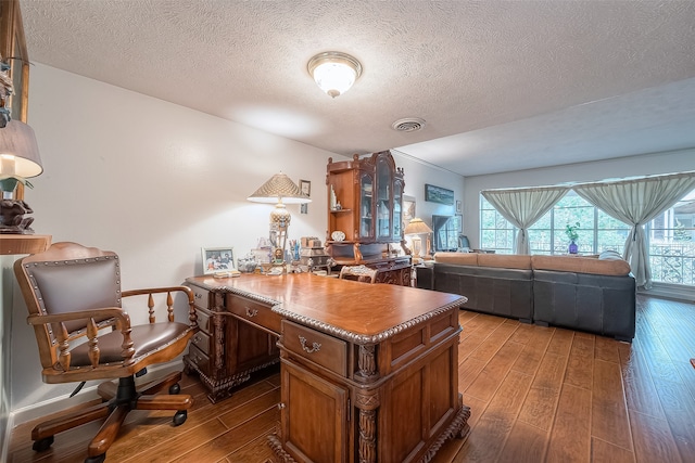 home office featuring hardwood / wood-style floors, built in desk, and a textured ceiling