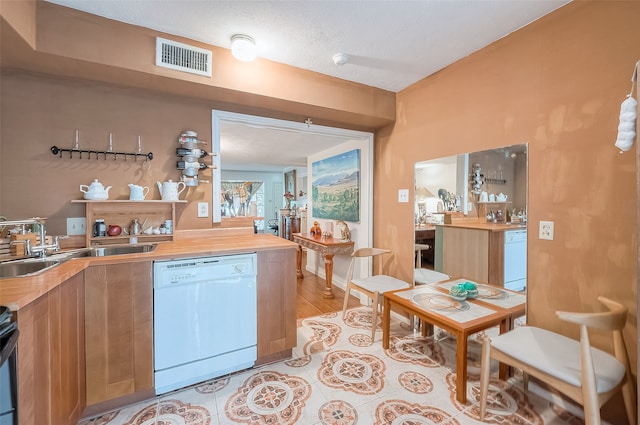 kitchen featuring dishwasher, wooden counters, a textured ceiling, and sink