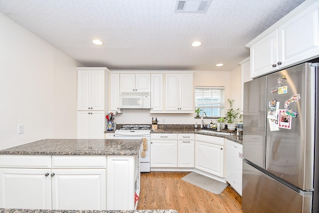 kitchen with white cabinets, white appliances, and a textured ceiling