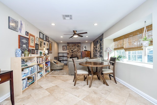 dining area featuring ceiling fan and a fireplace