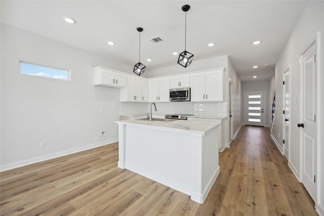 kitchen with light hardwood / wood-style flooring, pendant lighting, light stone countertops, and white cabinets