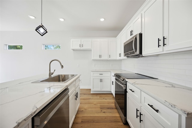 kitchen featuring light stone counters, appliances with stainless steel finishes, pendant lighting, sink, and white cabinets