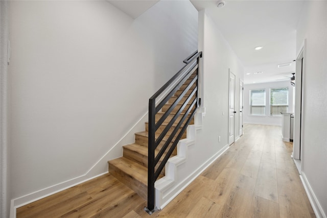 stairs featuring hardwood / wood-style flooring and ceiling fan