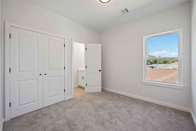 unfurnished bedroom with light colored carpet and a closet