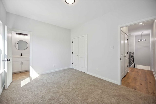 unfurnished bedroom with light colored carpet, ensuite bath, and a closet