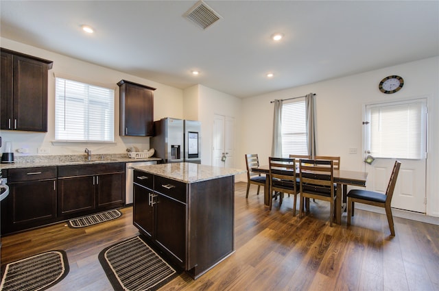 kitchen featuring dark wood-type flooring, a kitchen island, dark brown cabinets, and stainless steel appliances