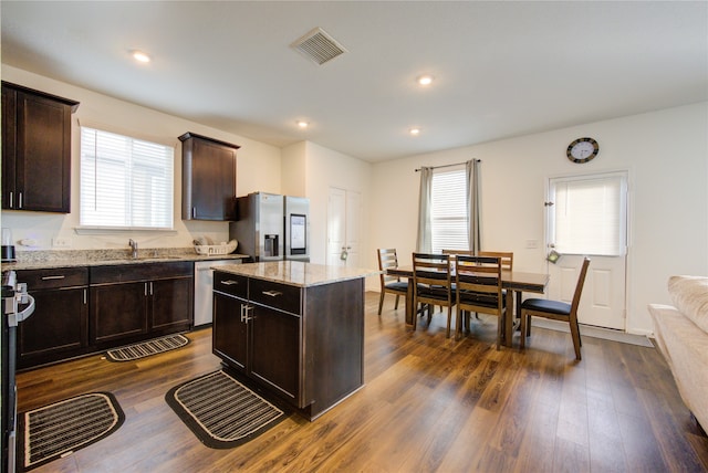 kitchen featuring stainless steel appliances, dark wood-type flooring, a center island, and plenty of natural light