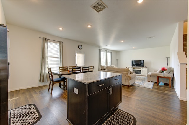 kitchen featuring dark hardwood / wood-style flooring, a kitchen island, a wealth of natural light, and dark brown cabinets