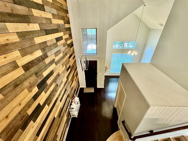 hall with high vaulted ceiling, dark hardwood / wood-style flooring, and an inviting chandelier