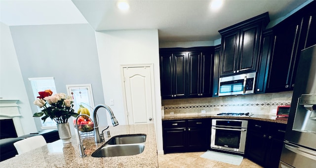 kitchen with light stone countertops, sink, backsplash, and appliances with stainless steel finishes