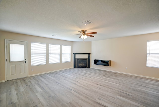 unfurnished living room featuring a textured ceiling, ceiling fan, and light hardwood / wood-style flooring