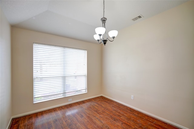 empty room featuring plenty of natural light, a notable chandelier, vaulted ceiling, and dark hardwood / wood-style flooring