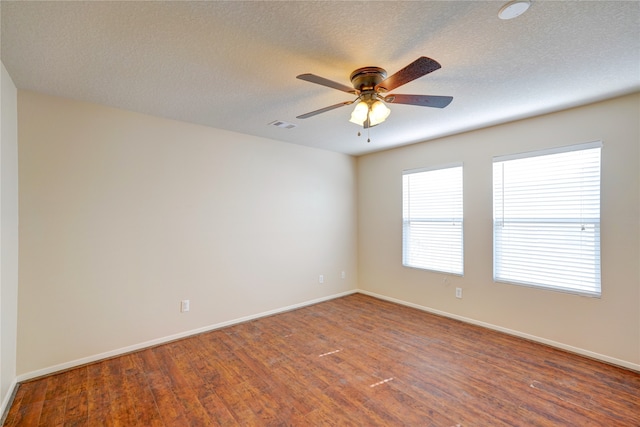 spare room with dark wood-type flooring, a textured ceiling, and ceiling fan