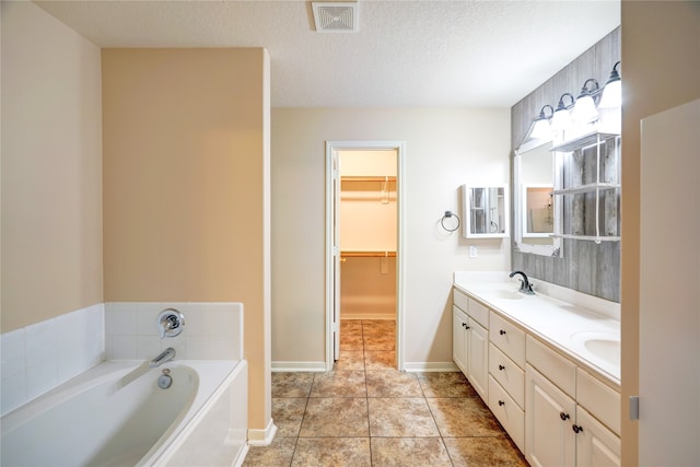 bathroom featuring vanity, a textured ceiling, tile patterned floors, and a bathing tub