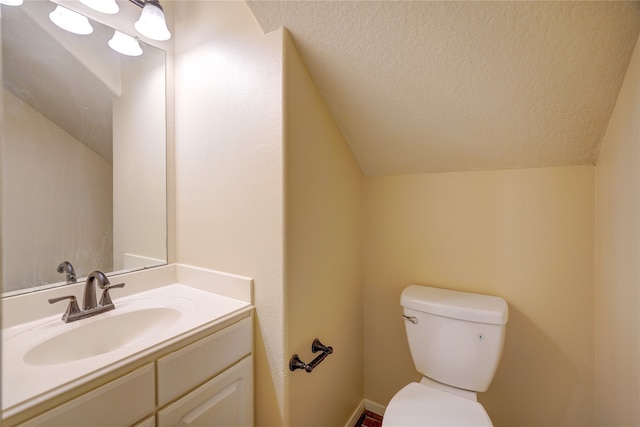 bathroom with vanity, a textured ceiling, toilet, and vaulted ceiling