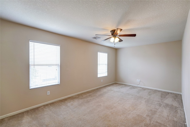 carpeted spare room featuring a textured ceiling and ceiling fan