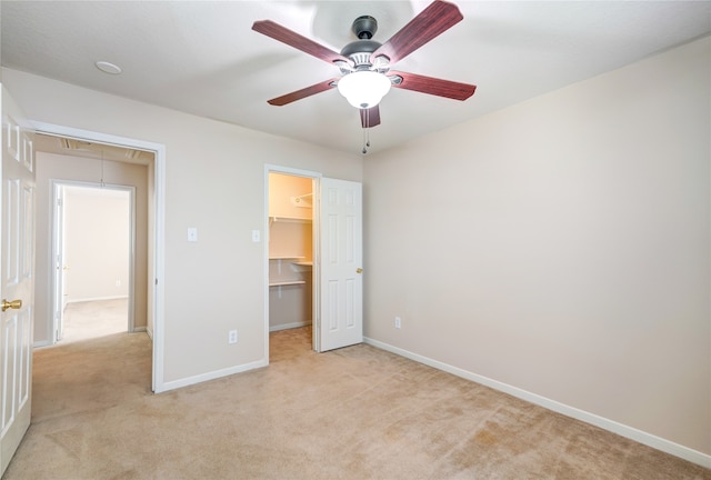 unfurnished bedroom with ceiling fan, light carpet, a closet, and a walk in closet