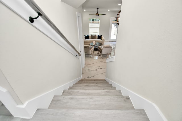 staircase featuring ceiling fan