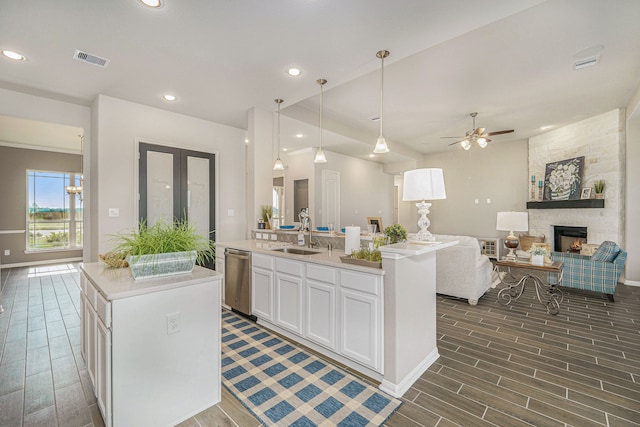 kitchen with dark wood-type flooring, white cabinetry, pendant lighting, and a center island with sink