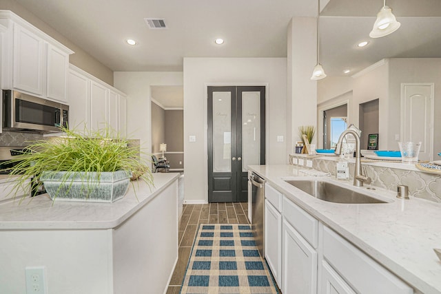 kitchen with pendant lighting, decorative backsplash, sink, white cabinetry, and appliances with stainless steel finishes