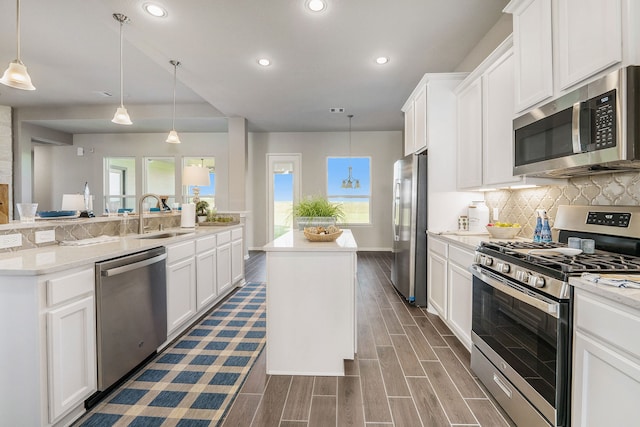 kitchen featuring sink, appliances with stainless steel finishes, a center island, white cabinets, and pendant lighting