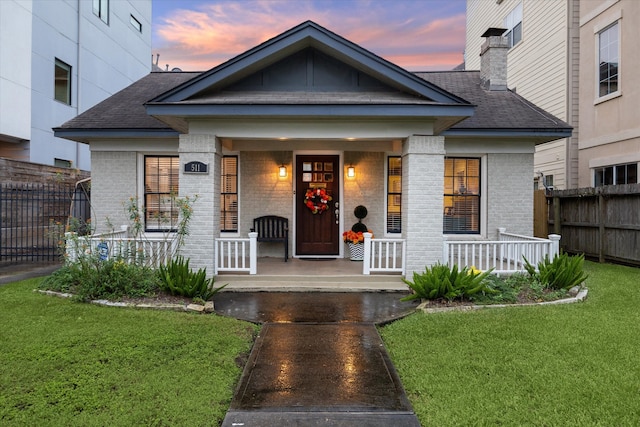 view of front of house featuring covered porch and a yard