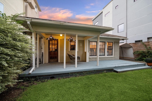 back house at dusk featuring a yard