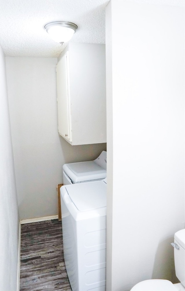 laundry room with a textured ceiling, washing machine and dryer, and dark hardwood / wood-style floors