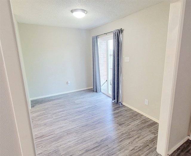 spare room with a textured ceiling and light hardwood / wood-style flooring