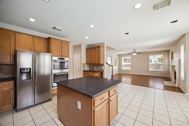 kitchen with ceiling fan, a center island, light tile patterned floors, and appliances with stainless steel finishes