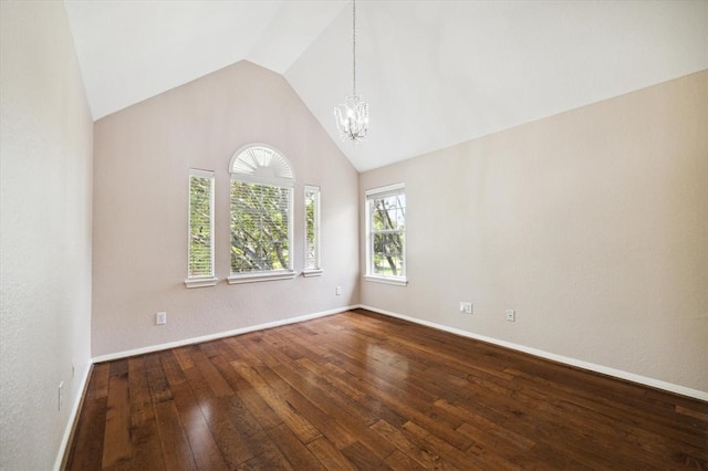 spare room featuring hardwood / wood-style floors, lofted ceiling, and a notable chandelier