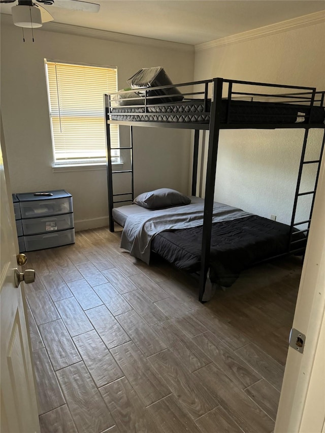 bedroom with ceiling fan, crown molding, and wood-type flooring