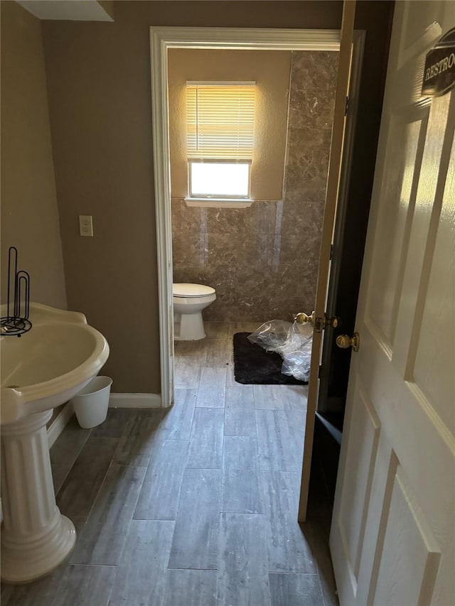 bathroom featuring hardwood / wood-style floors, toilet, and tile walls