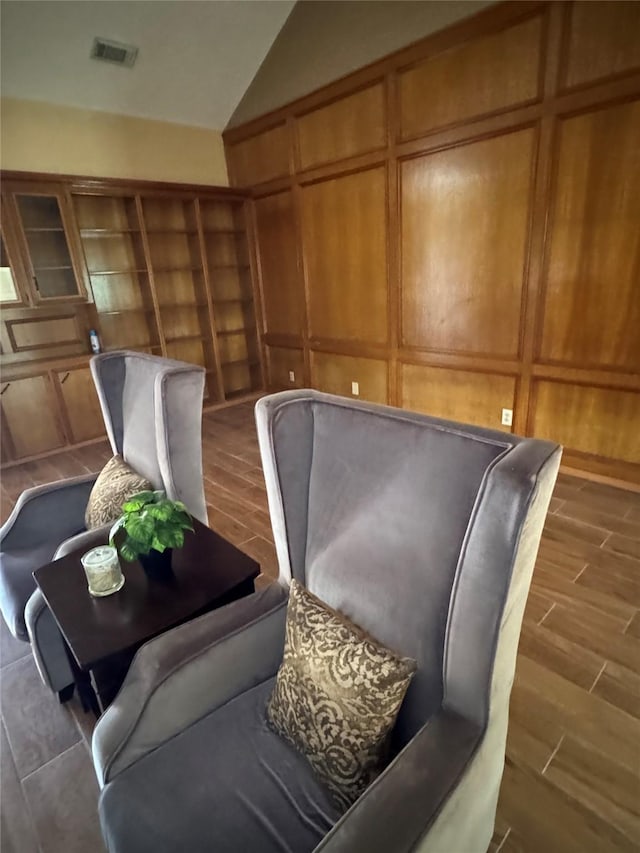 living area with wooden walls, vaulted ceiling, and dark wood-type flooring