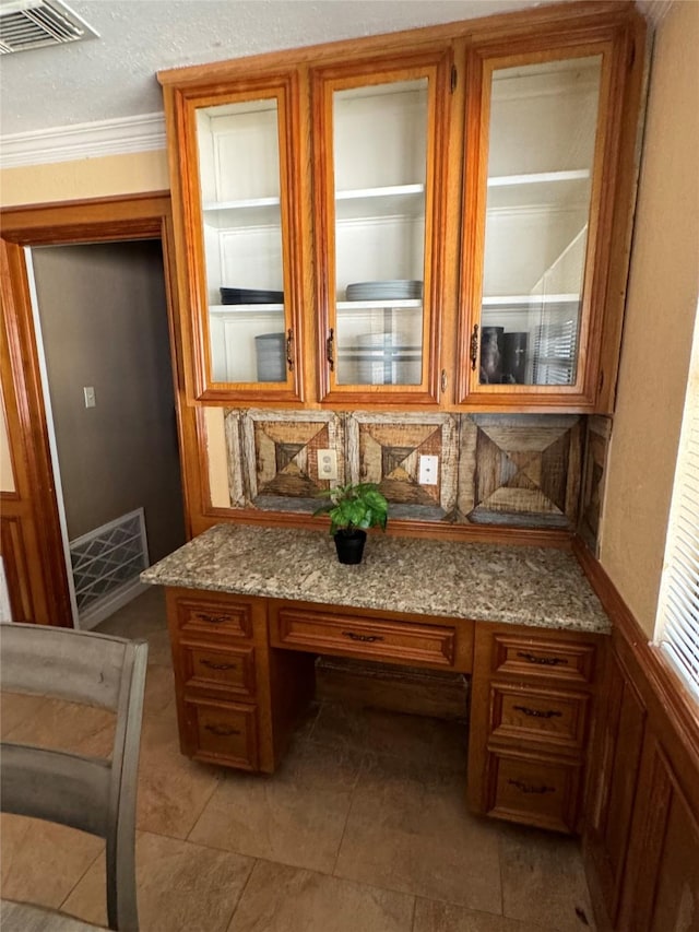 kitchen featuring light stone countertops, built in desk, and crown molding