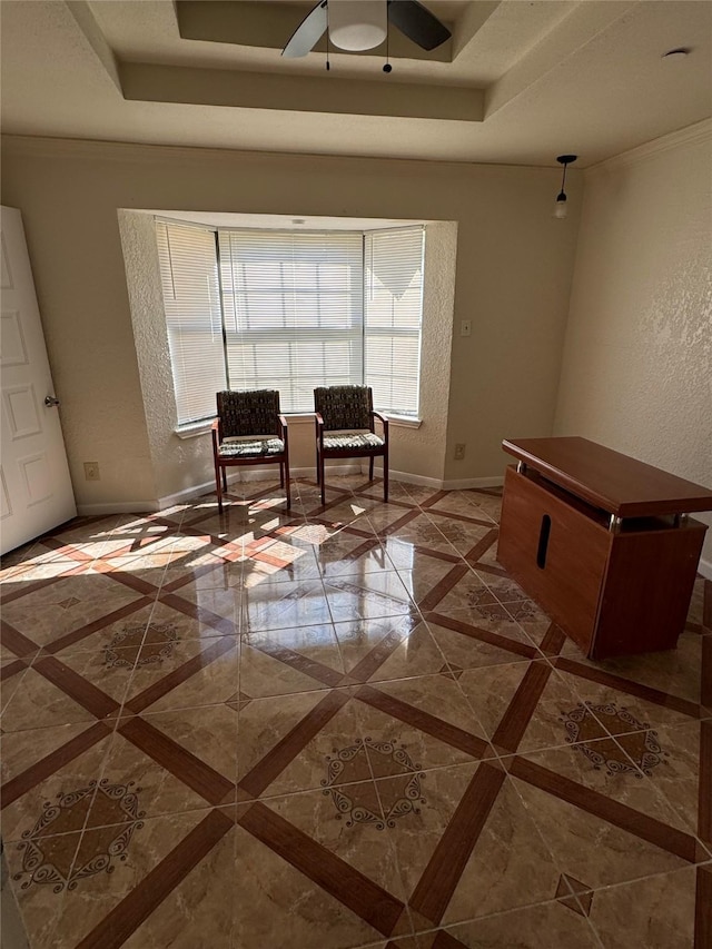 sitting room with a tray ceiling, ceiling fan, and ornamental molding