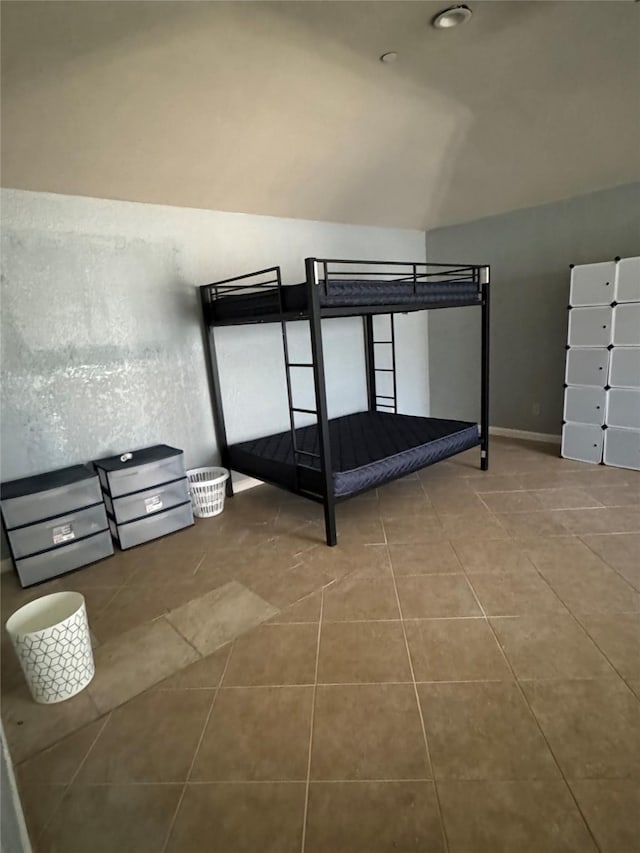 unfurnished bedroom with tile patterned floors and vaulted ceiling